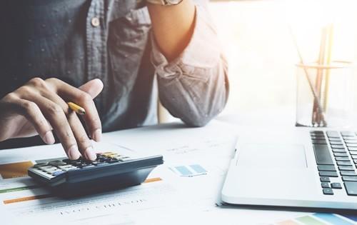 Person sitting with a calculator at a desk